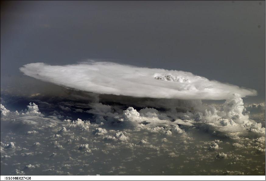 Figure 63: A cumulonimbus cloud over Africa photographed by an astronaut on the International Space Station. Deemed by many meteorologists as one of the most impressive of cloud formations, cumulonimbus (from the Latin for ‘puffy' and ‘dark') clouds form owing to vigorous convection of warm and moist unstable air. Air warmed by the ground rises, with water droplets condensing as the rising air encounters cooler air at higher altitudes. The air mass itself also expands and cools as it rises owing to decreasing atmospheric pressure. This type of convection is common in tropical latitudes (image credit: NASA)