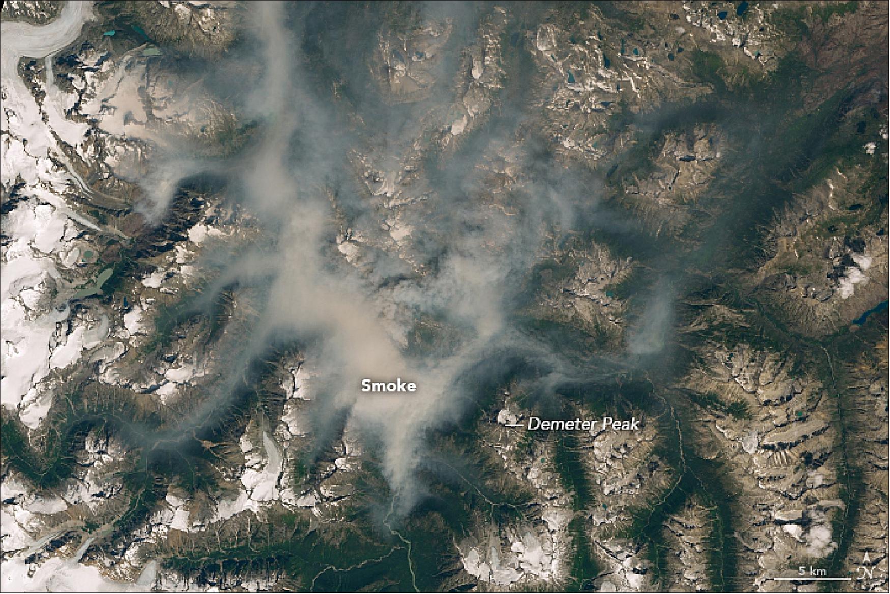 Figure 13: OLI (Operational Land Imager) on Landsat-8 captured this natural-color image of smoke lingering in valleys near the snow-capped peaks of the Coast Mountains on August 7, 2018 (image credit: NASA Earth Observatory image by Lauren Dauphin using Landsat data from the U.S. Geological Survey, story by Adam Voiland)