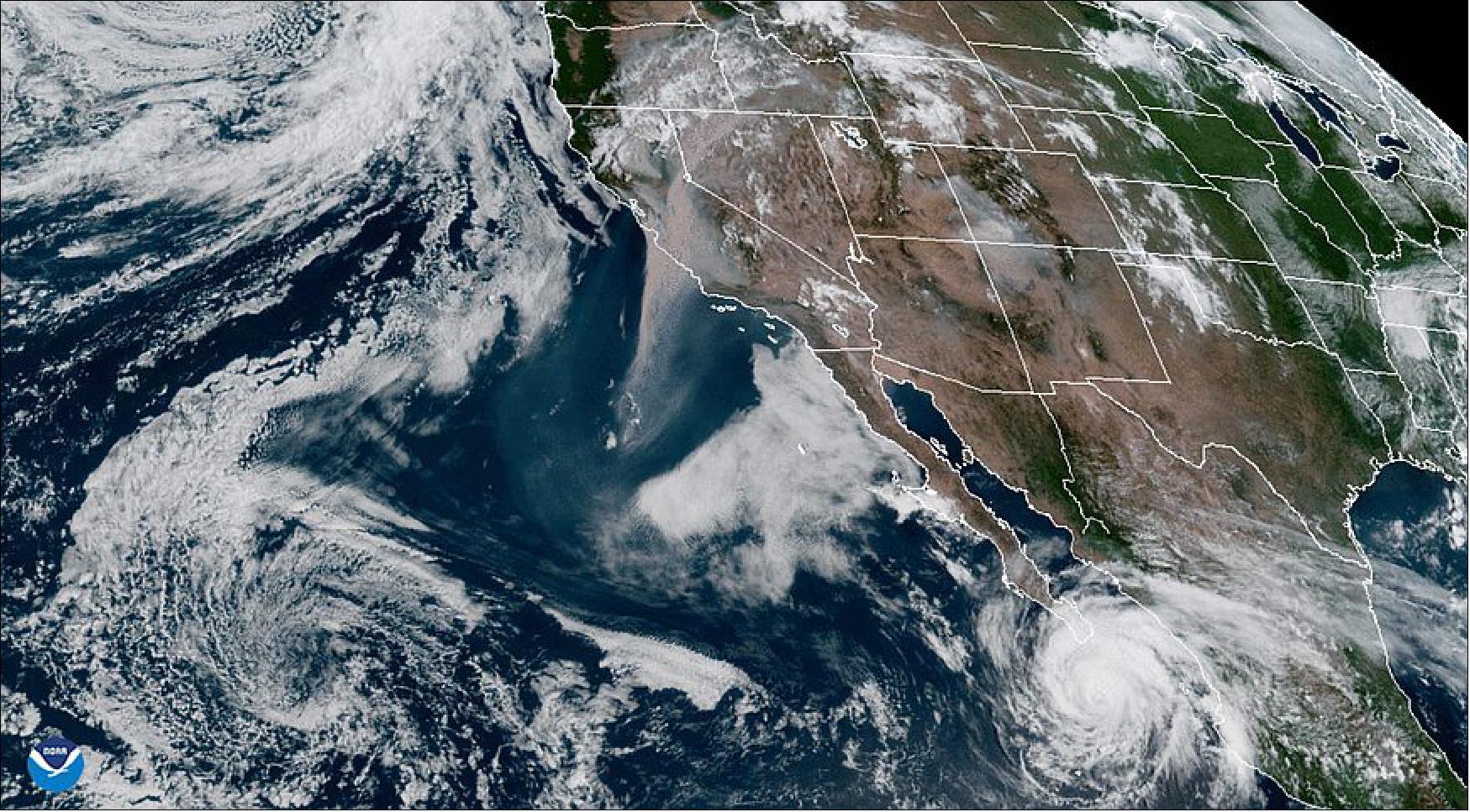Figure 25: NOAA’s GOES-West satellite (GOES-17) captured the above GeoColor image of massive wildfire smoke plumes billowing from California and areas of the Rocky Mountains on Aug. 19, 2020. To the north, a mid-latitude cyclone spins over the Gulf of Alaska while Hurricane Genevieve continues its path toward Baja California (image credit: NOAA)